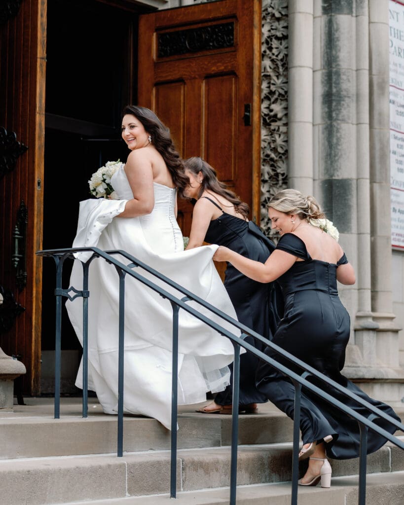 Bride walking up cathedral steps with bridesmaids