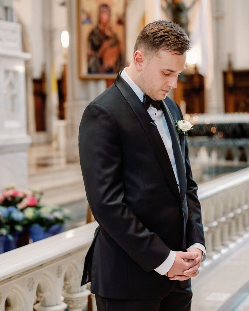 Groom standing inside cathedral before ceremony