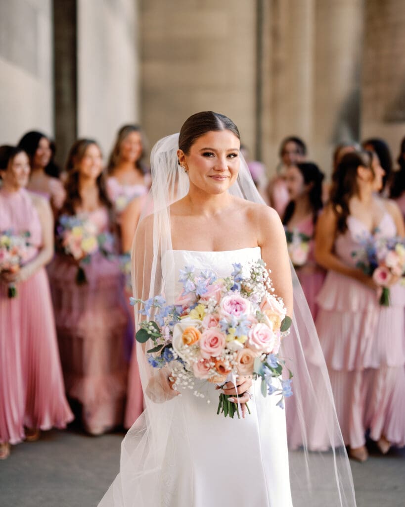 Bride holding bouquet with bridesmaids in background at Mellon Institute Columns Pittsburgh