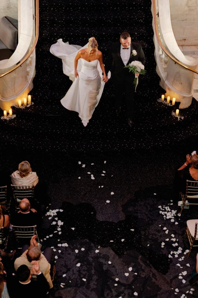 Bride and groom walking down grand staircase during ceremony at Renaissance Hotel Pittsburgh