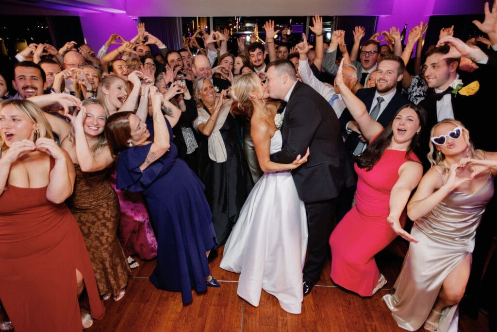 Bride and groom kissing surrounded by cheering guests at Pittsburgh wedding reception